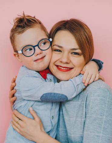 A child with glasses hugging a woman