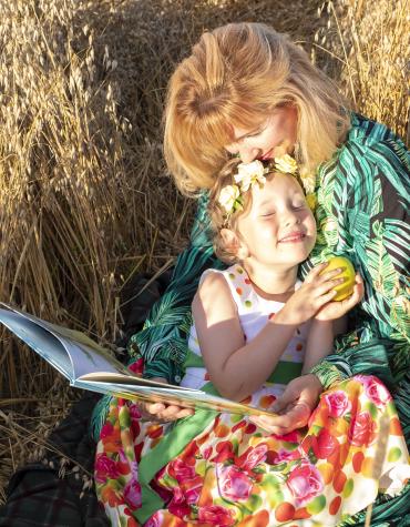 An adult and child reading in the August sunshine