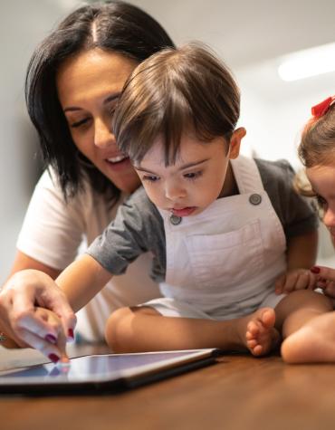 Adult helping young children use an iPad