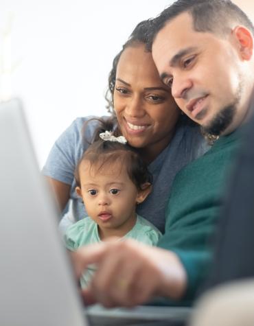 Two adults with child playing on the computer