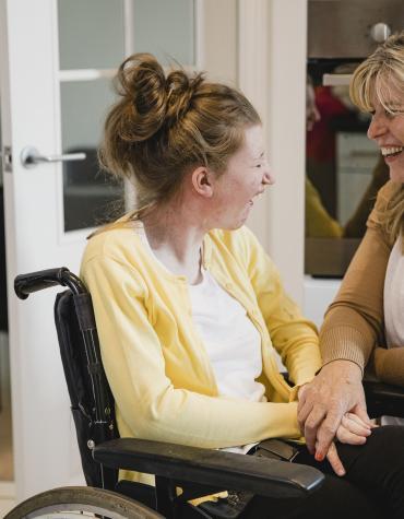 Young female in wheelchair laughing with adult female 