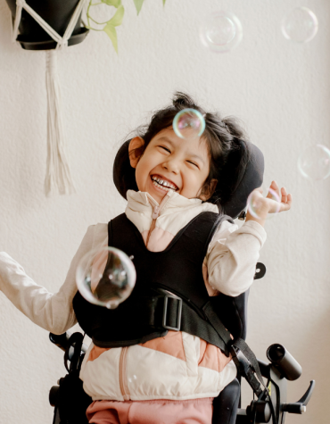 Young girl smiling in wheelchair with bubbles 