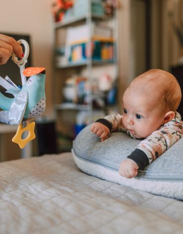 Newborn laying on tummy looking at toy