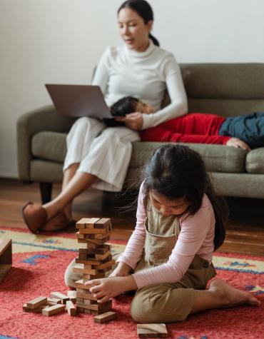 Parent on computer while child plays with blocks