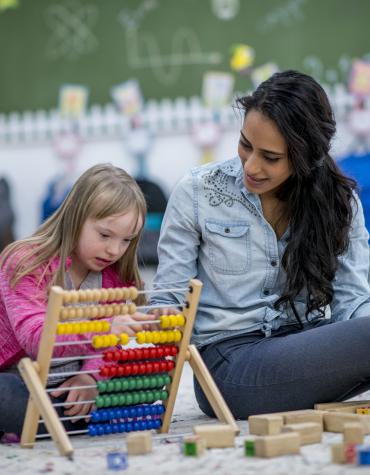 Adult and child in a classroom using slider beads