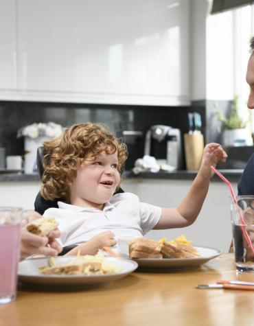 child and two adults eating dinner