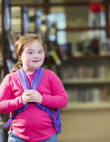 child with backpack in library