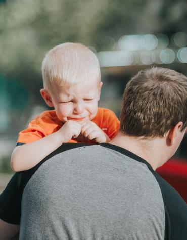 Man carrying upset young child