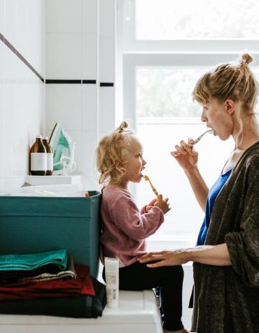 Toddler and adult brushing their teeth in a bathroom