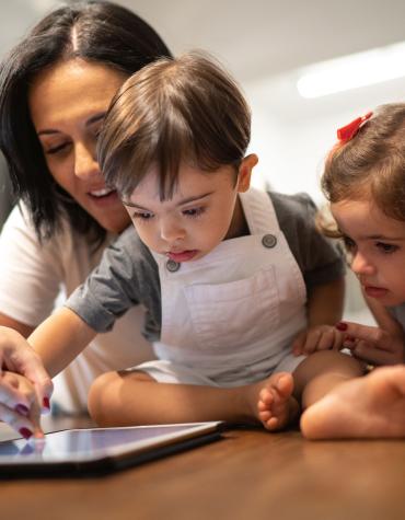 Young boy using iPad with mom and young girl