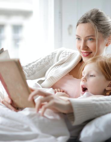 child and adult reading book together