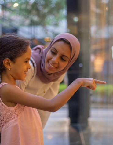 child pointing at something in store window and showing adult