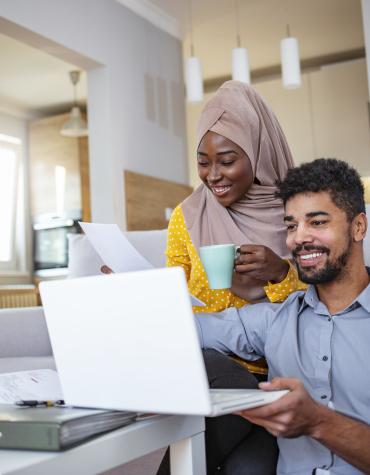 two adults looking at a laptop with smiles