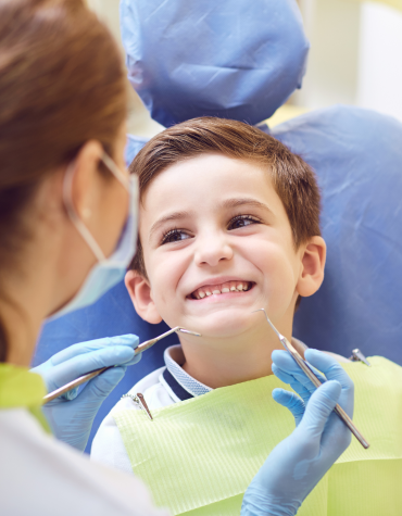 young boy sitting in the dentist chair smiling