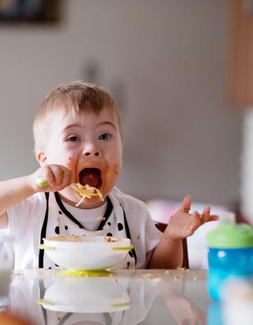 child eating pasta with food on face