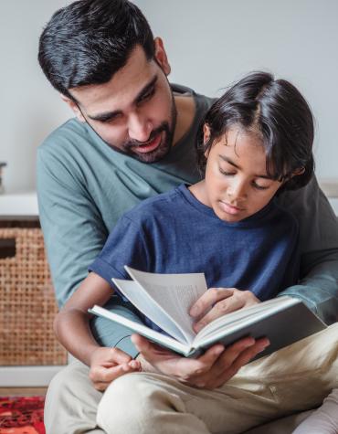 Child sitting on adults lap flipping through book