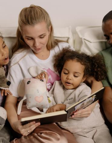 Family reading a book together with stuffed animals