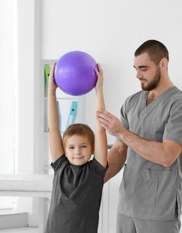 Physiotherapist with child holding ball above head
