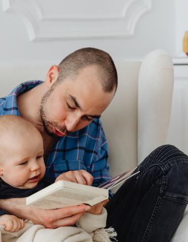 Adult reading to baby and pointing at the book