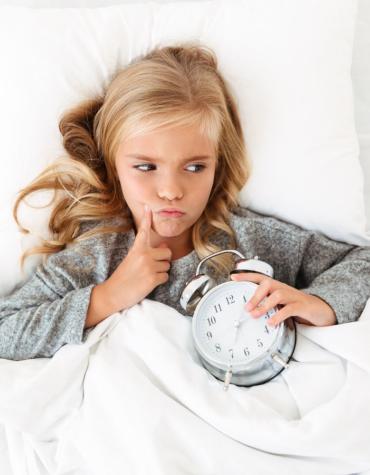 girl in bed with clock